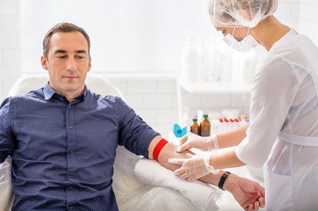 female doctor takes blood sample from male patient