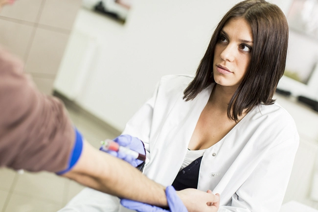 female doctor takes blood sample while looking at patient
