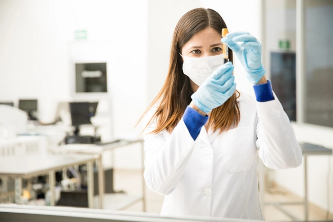 female examines blood sample in lab