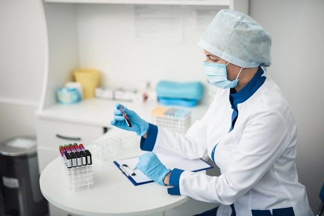 female facility assistant looking at test tube of blood in lab office