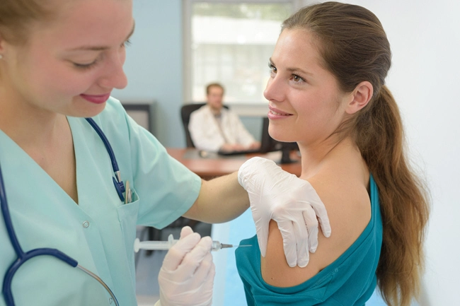 happy doctor giving an injection to female patient at office