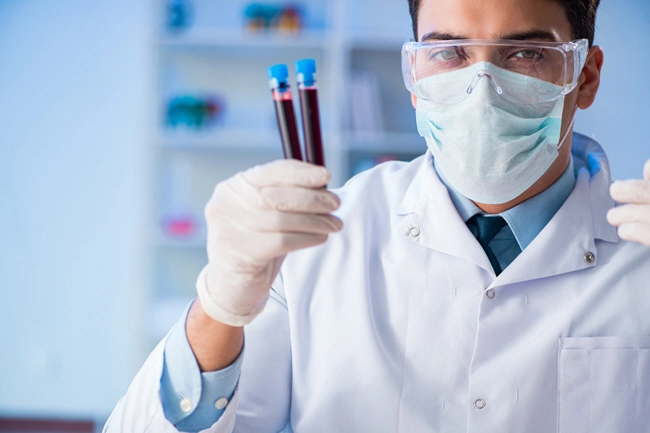 male doctor holding two tubes of blood