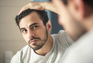 storyblocks latino person with beard grooming in bathroom at home white metrosexual man worried for hair loss and looking at mirror his receding hairline_H8mcRKLWQ 300x203