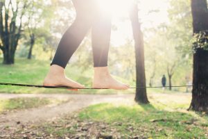 graphicstock close up on feet walking on tightrope or slackline outdoor in a city park in back light slacklining balance training concept_S6lDgAiKJZ 300x200